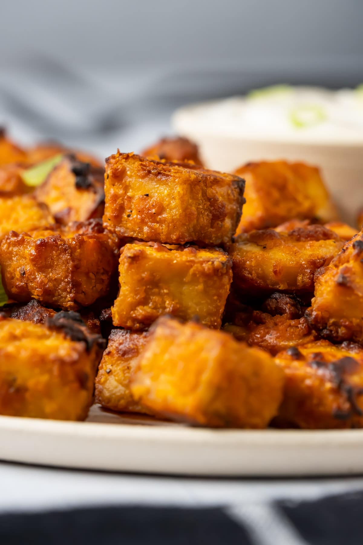 Air fryer tofu with ranch dressing and chopped green onions on a white plate.