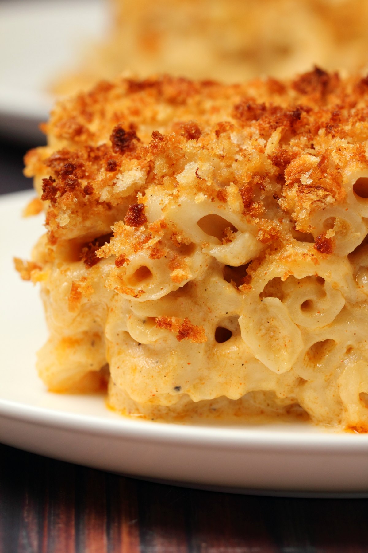 A slice of baked vegan mac and cheese on a white plate. 