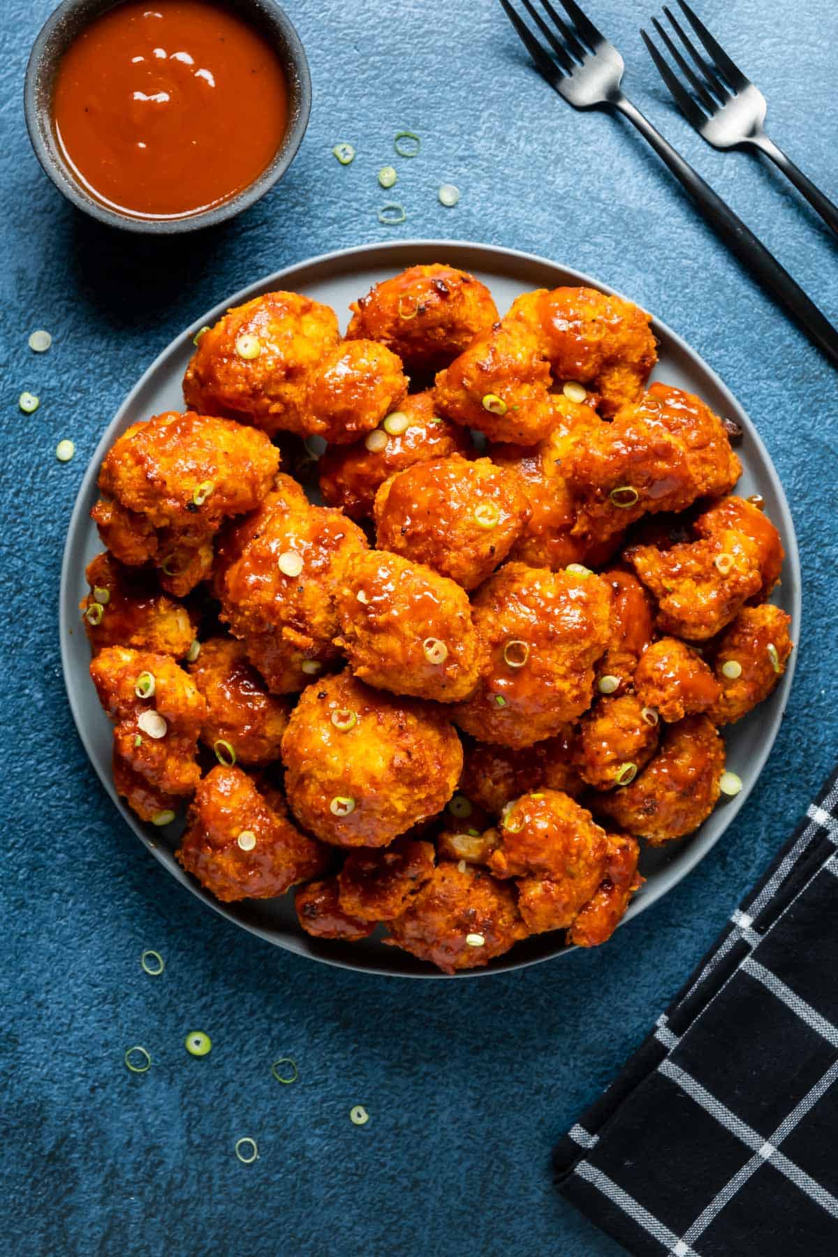 BBQ cauliflower wings stacked up on a plate.