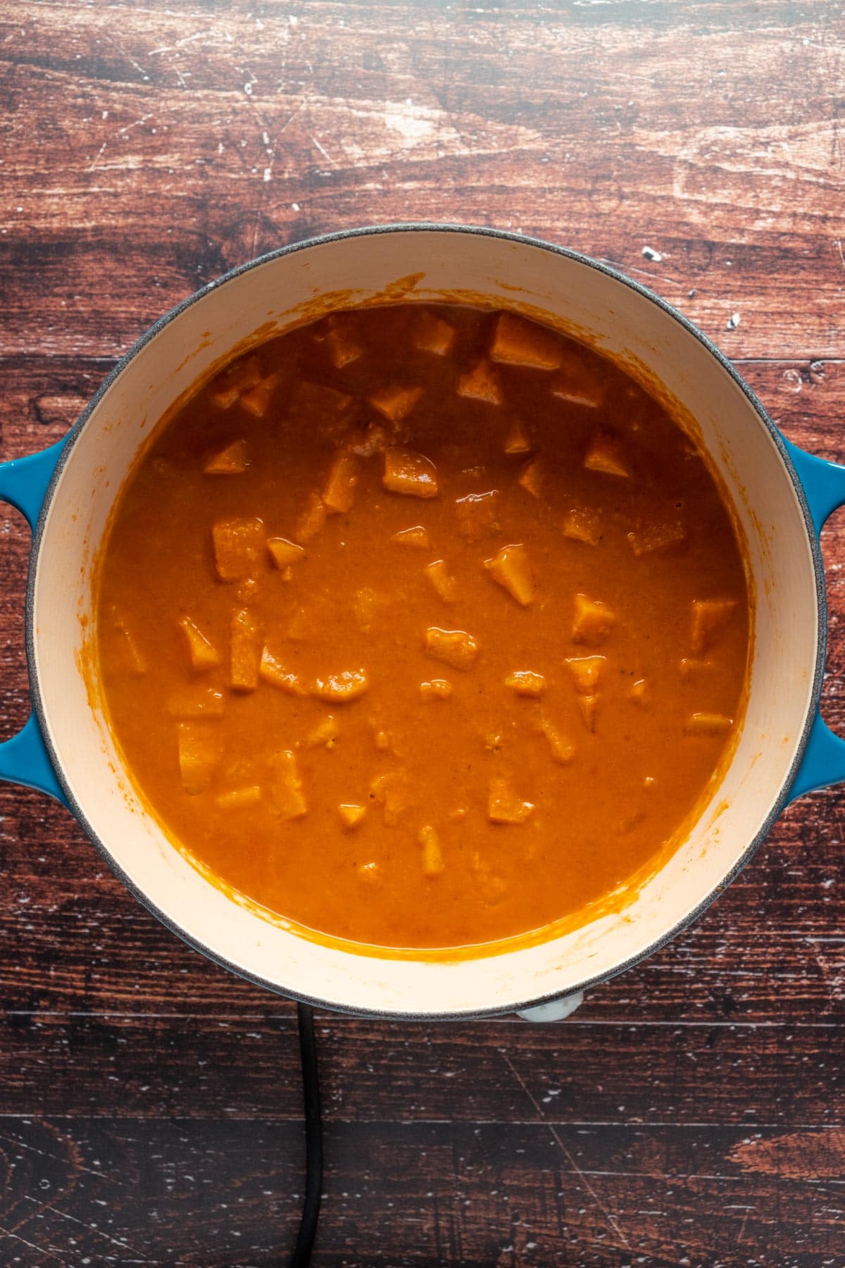 Butternut squash curry cooking in a ceramic pot.