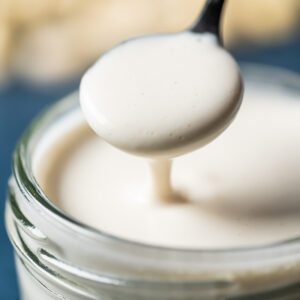 Vegan heavy cream substitute in a glass jar with a spoon.