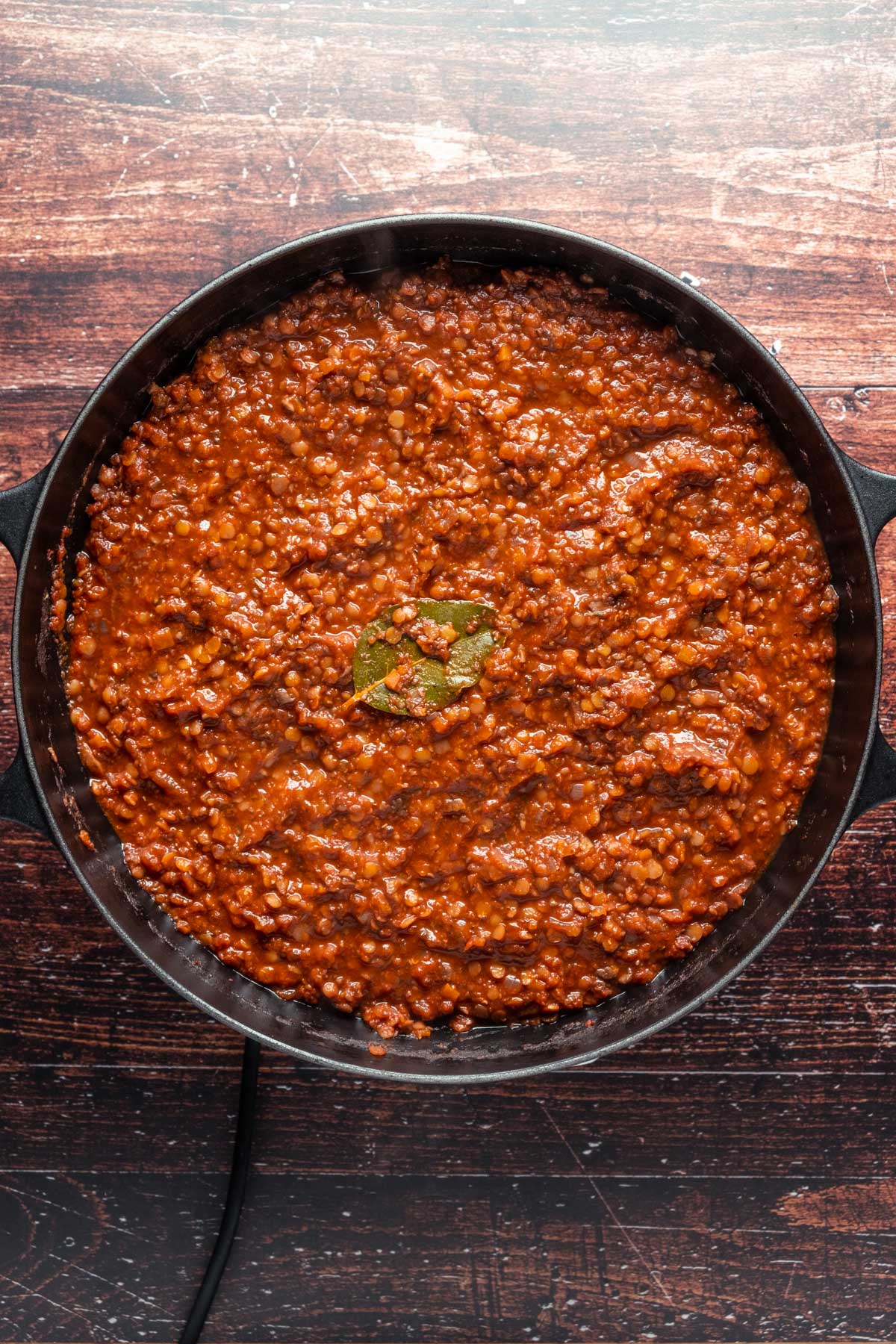 Lentil ragu sauce with a bay leaf in a large skillet.