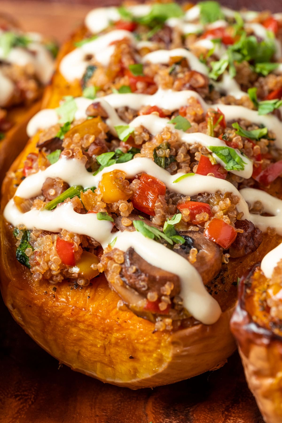 Stuffed butternut squash drizzled with cashew cream and sprinkled with fresh chopped cilantro on a serving platter. 