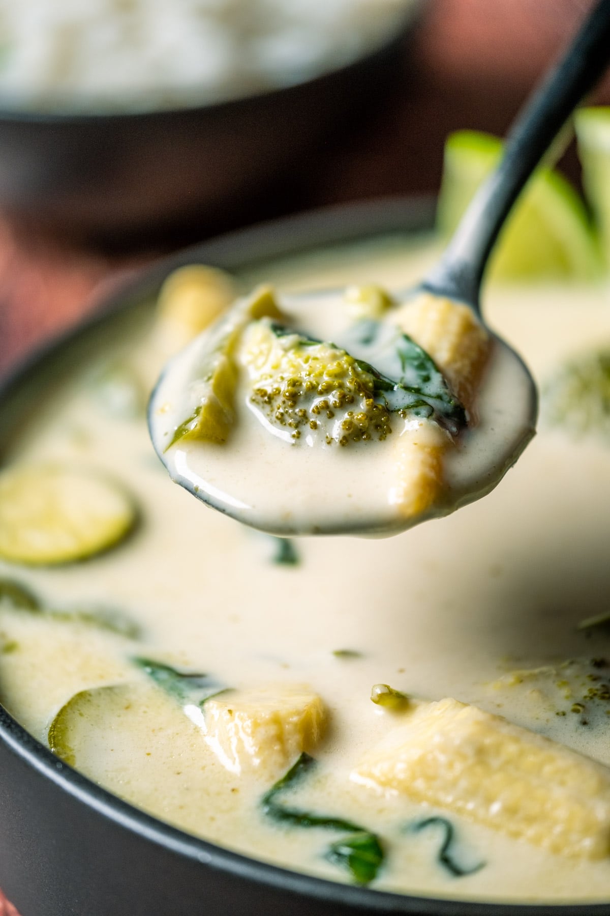 Vegan Thai green curry in a black bowl with a spoon.