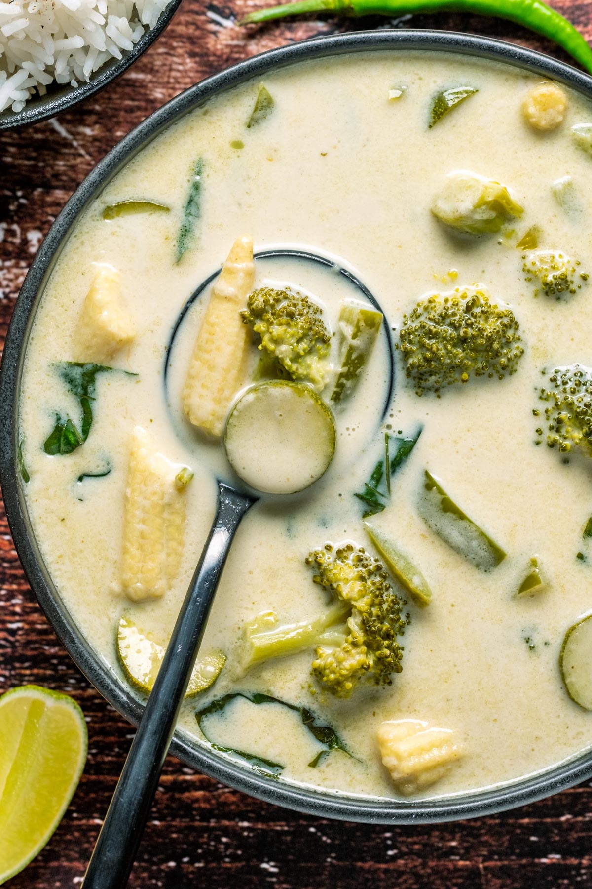 Vegan Thai green curry in a black bowl with a spoon.