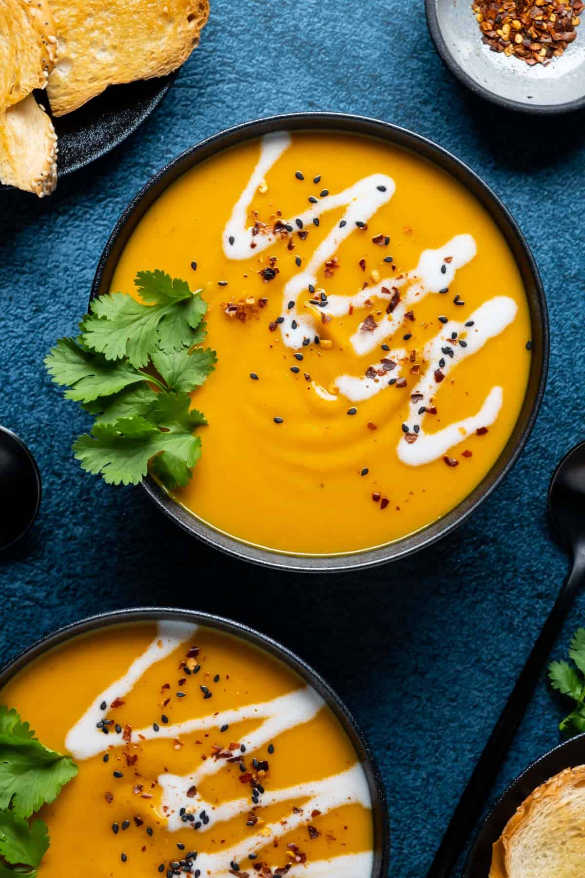 Thai sweet potato soup topped with fresh cilantro in black bowls.