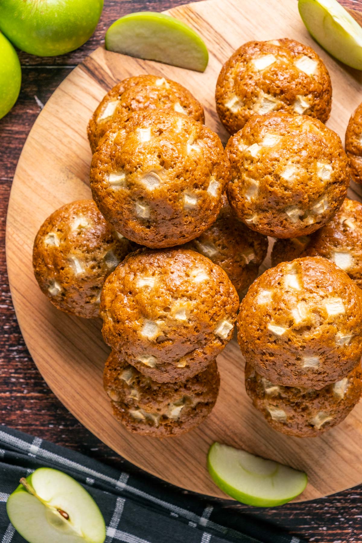 Vegan apple muffins stacked up on a wooden board.