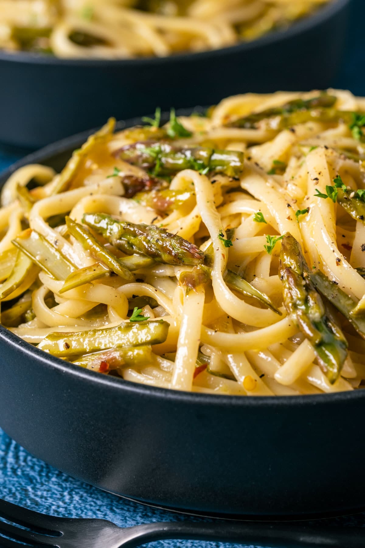 Vegan asparagus pasta in a black bowl.