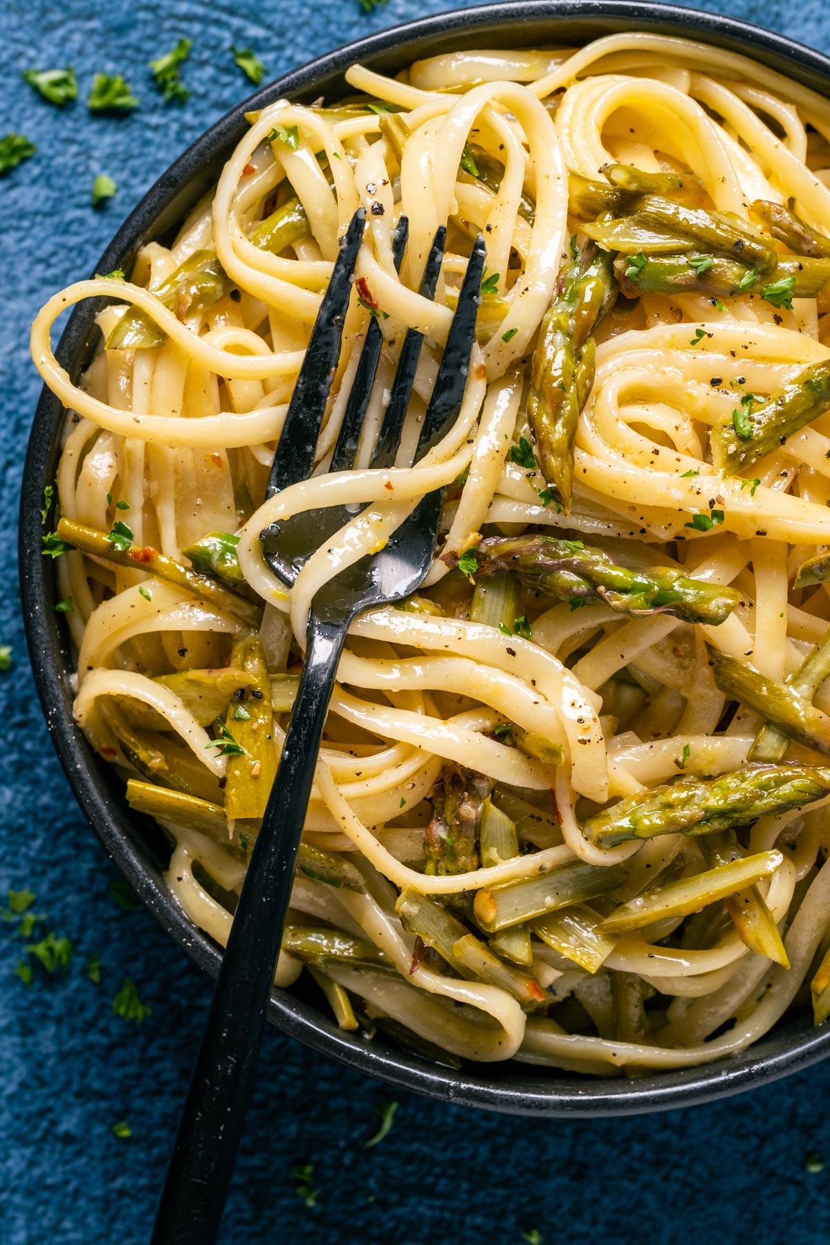 Vegan asparagus pasta in a black bowl with a fork.