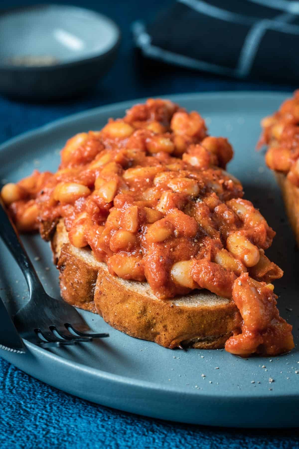 Toast topped with baked beans on a blue plate.