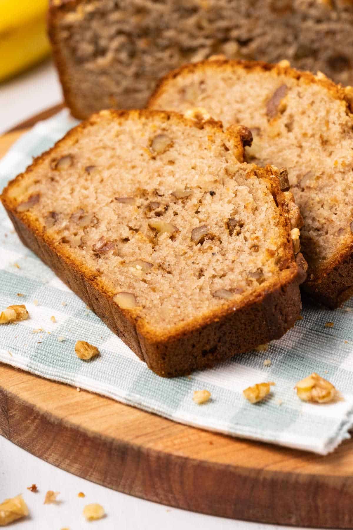 Slices of banana bread on a napkin and wooden board. 