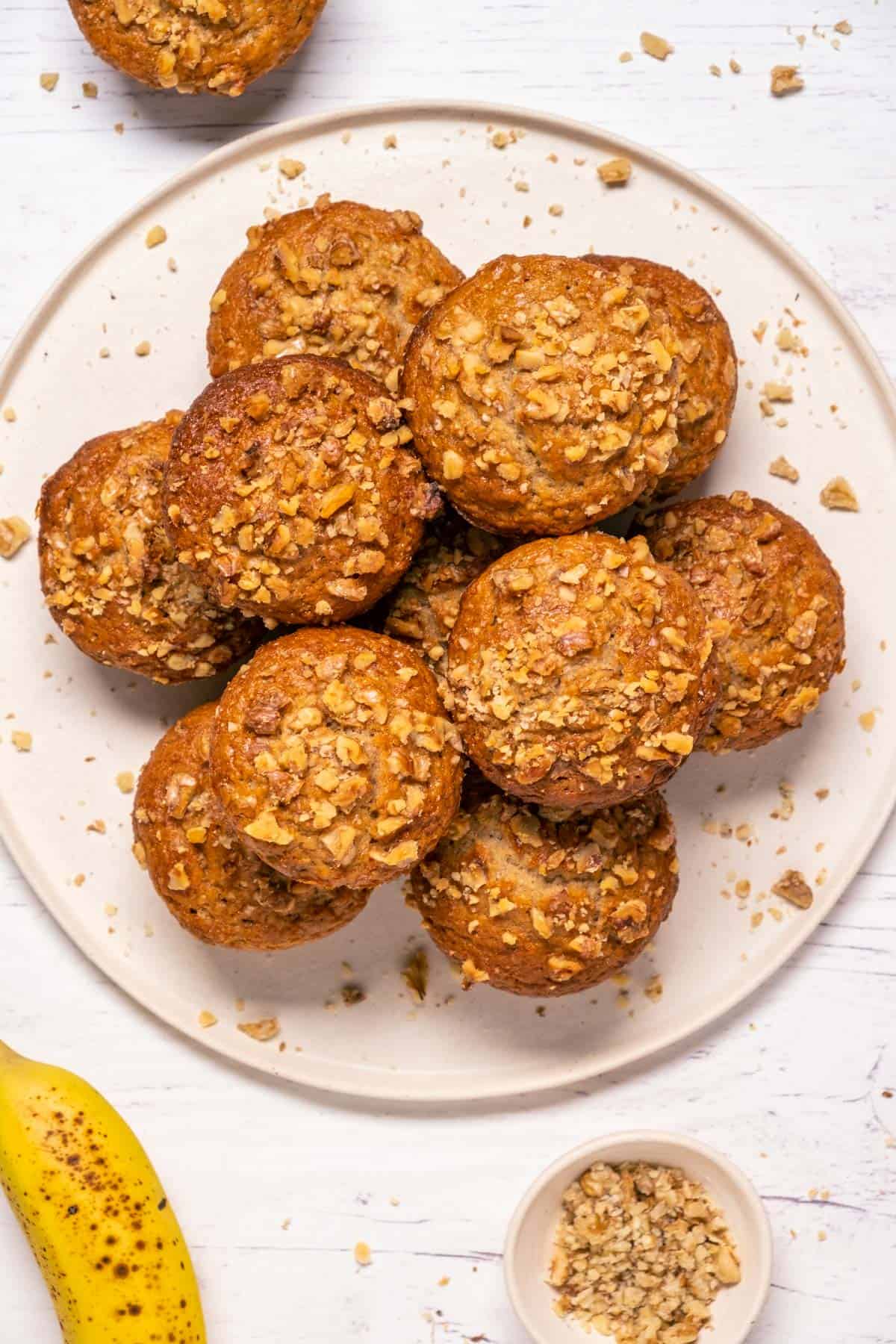 Vegan banana bread muffins stacked up on a white plate.