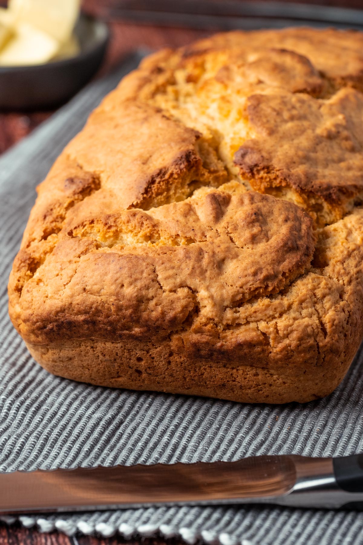 Loaf of vegan beer bread on a napkin with a knife.