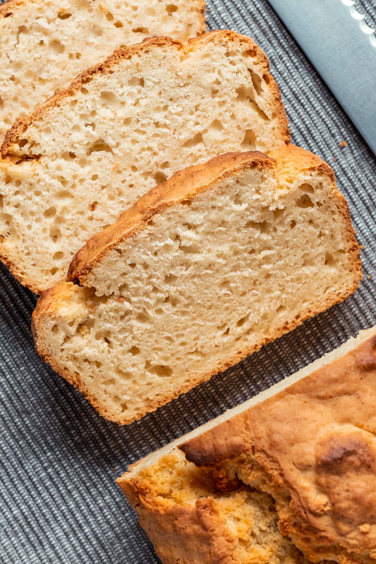 Sliced vegan beer bread on a napkin with a bread knife. 