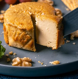 Brie cheese on a plate with one slice cut.