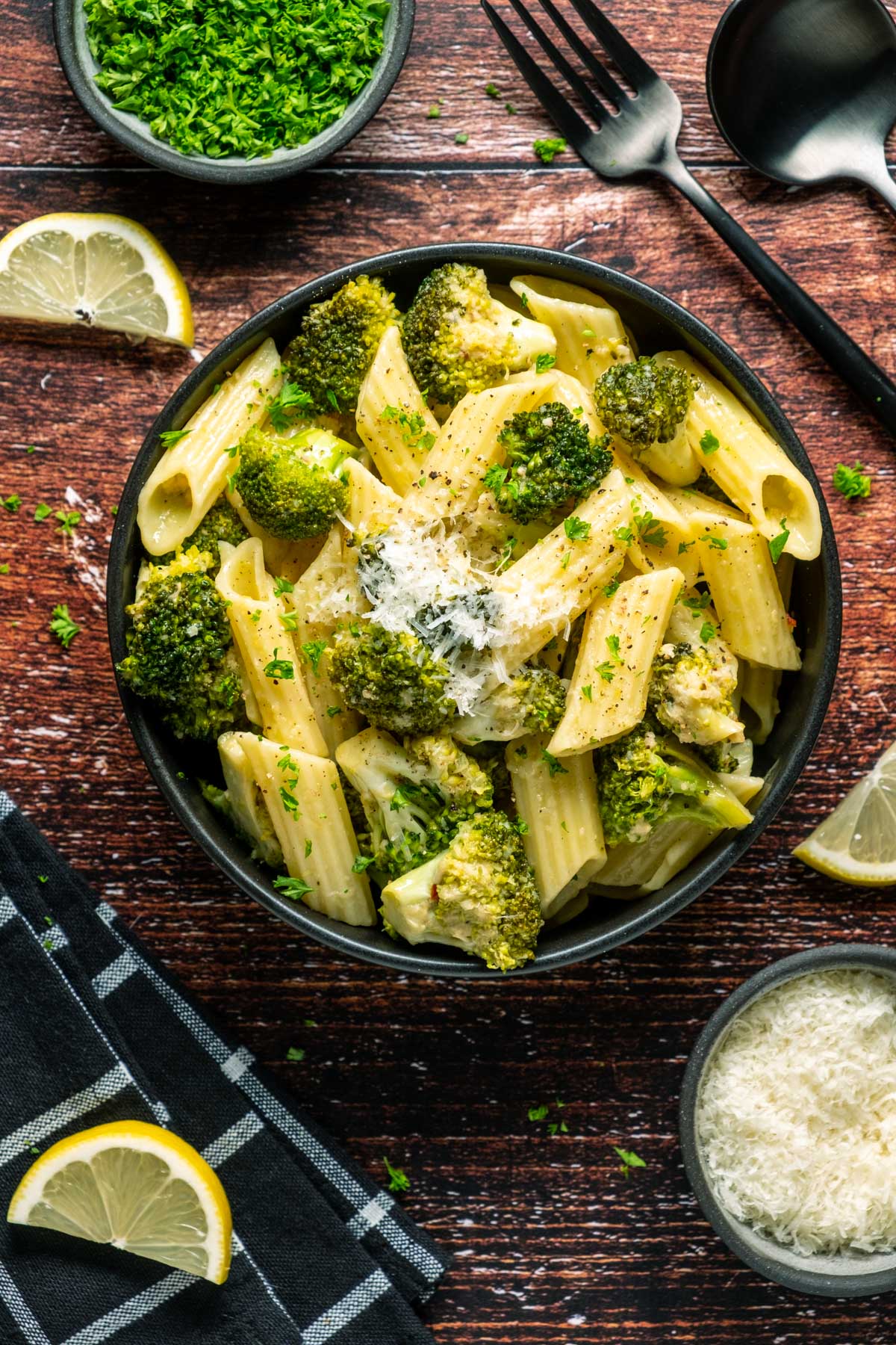 Vegan broccoli pasta topped with vegan parmesan in a black bowl.