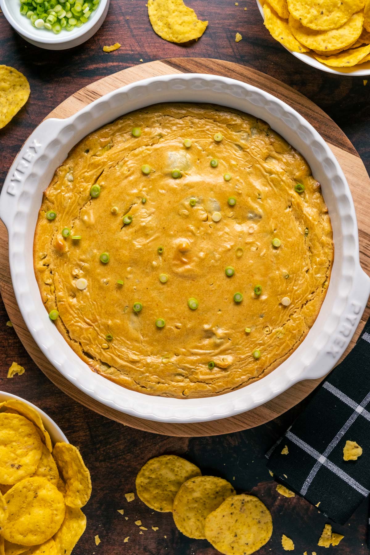 Vegan buffalo chicken dip in a white dish topped with chopped green onions.