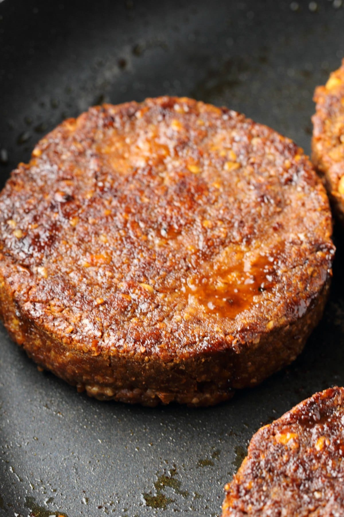 Vegan burgers cooking in a frying pan. 