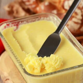 Homemade vegan butter in a glass butter dish with a knife.