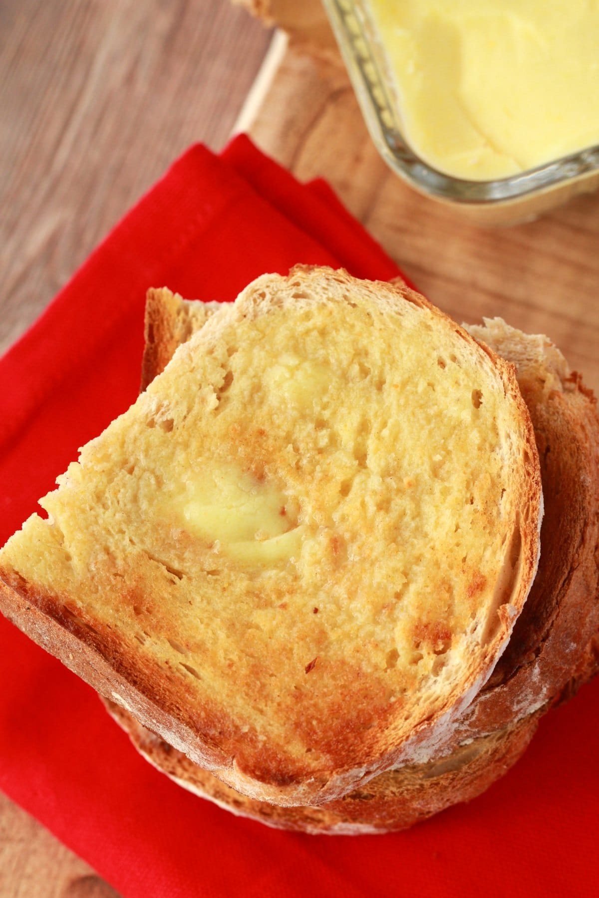 Slices of toast spread with vegan butter on top of a red napkin. 