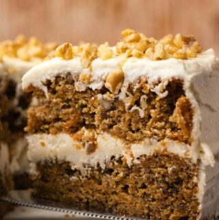 Sliced carrot cake on a white cake stand.