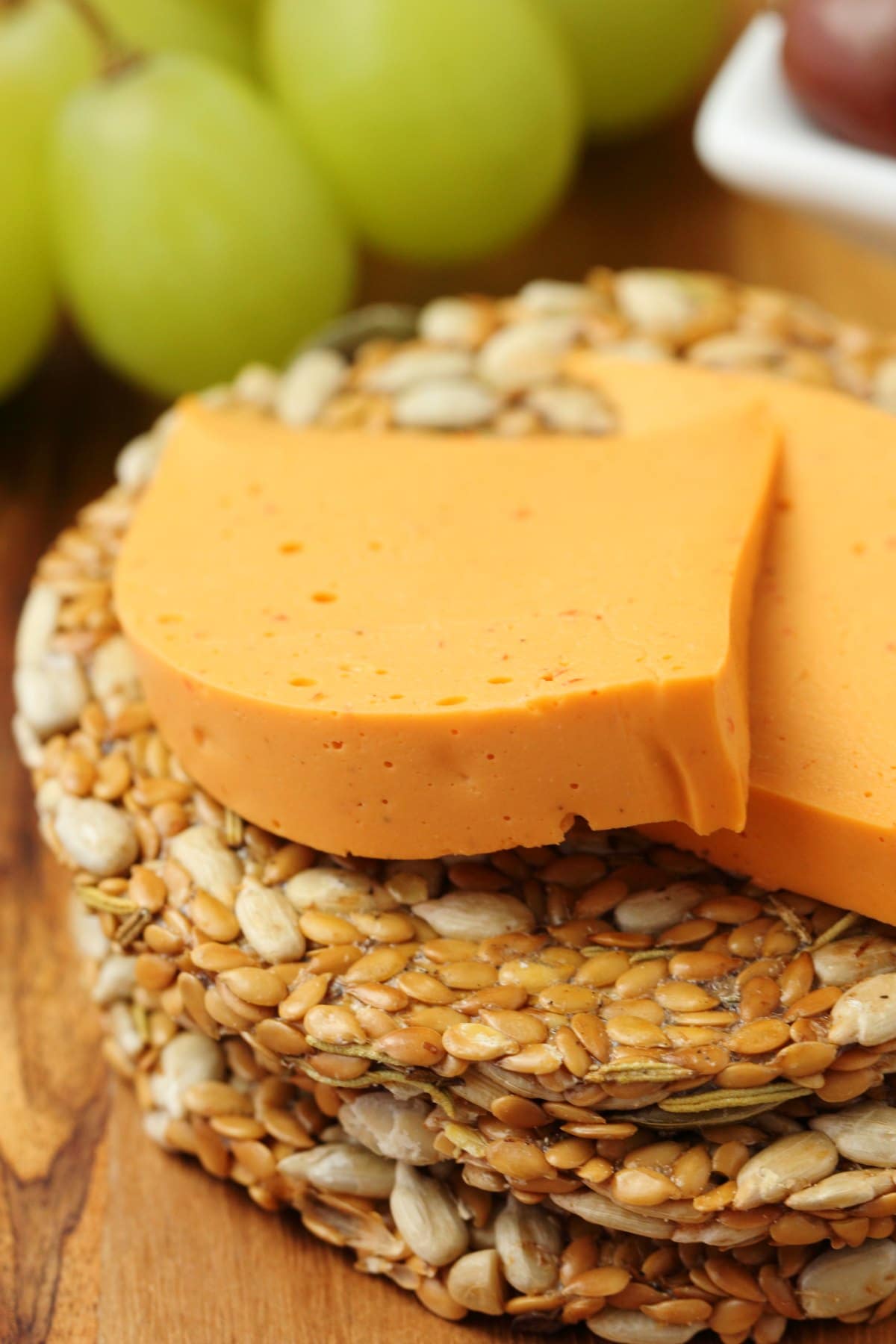 Vegan cheddar cheese slices on top of seed crackers. 