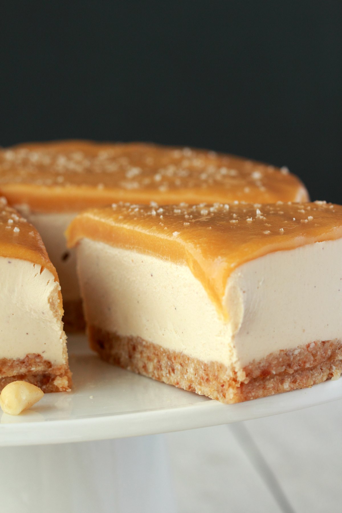 Cheesecake on a white cake stand with one slice cut and ready to be served. 