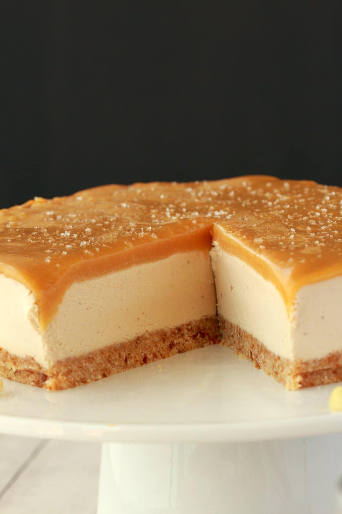 Cheesecake on a white cake stand with one slice removed.