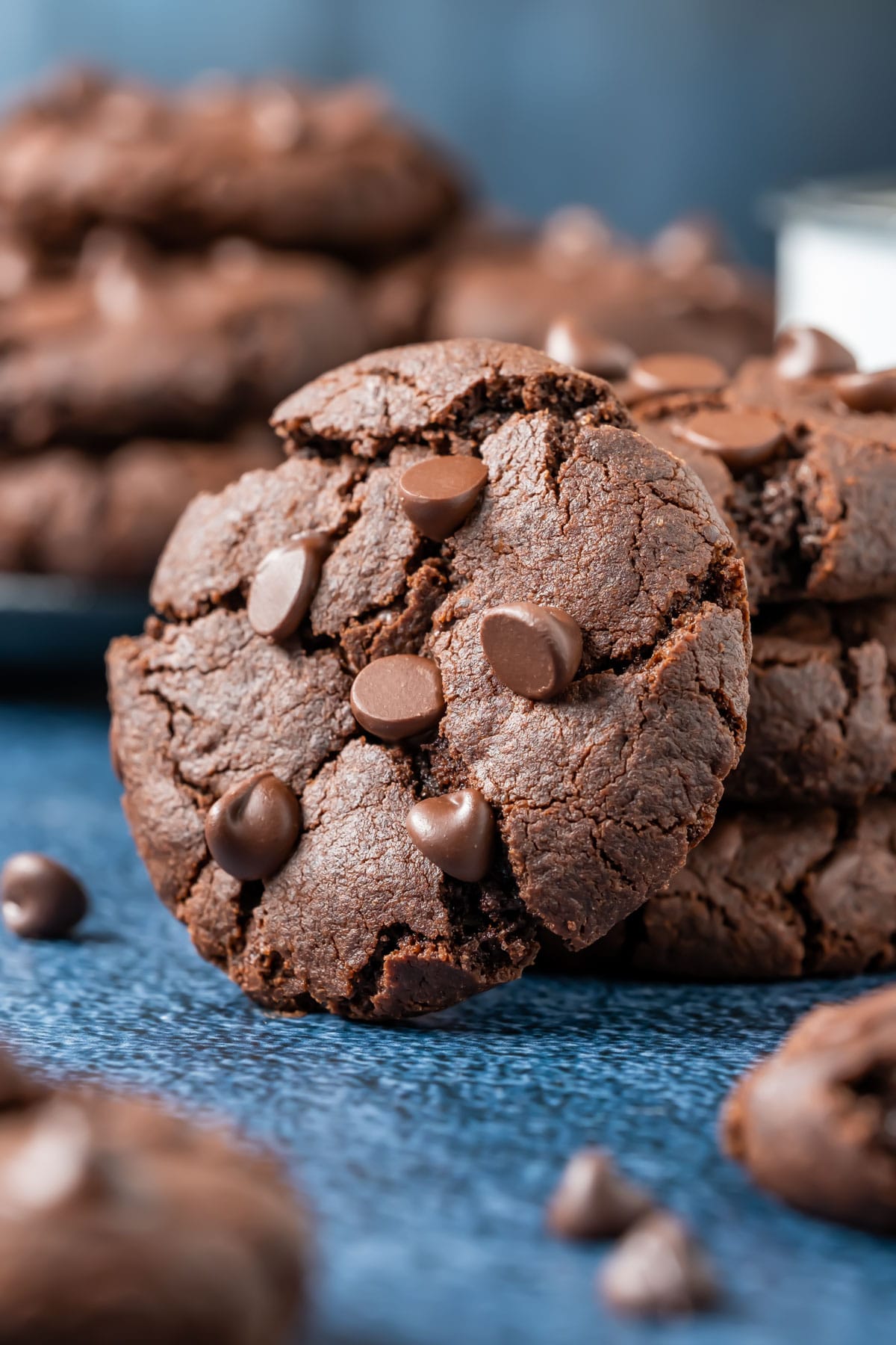 A vegan chocolate cookie leaning against a stack of cookies.