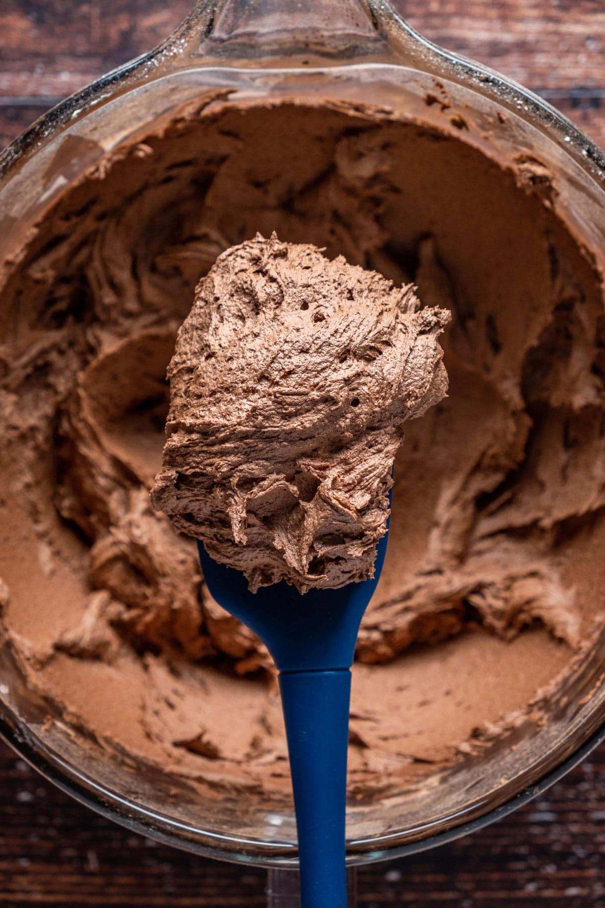 Vegan chocolate fudge frosting in a stand mixer with a spatula.