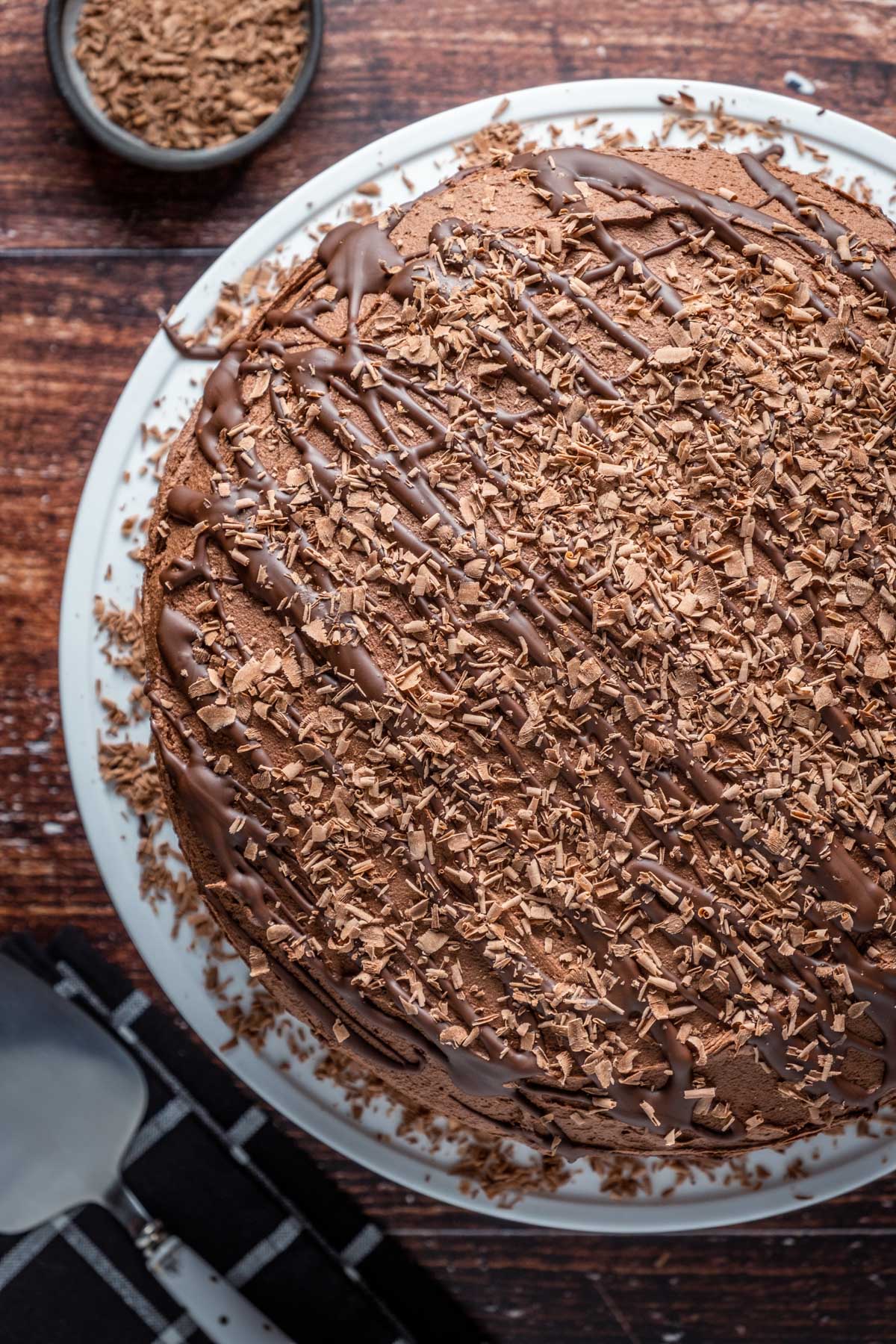 Frosted and decorated chocolate fudge cake on a white cake stand.