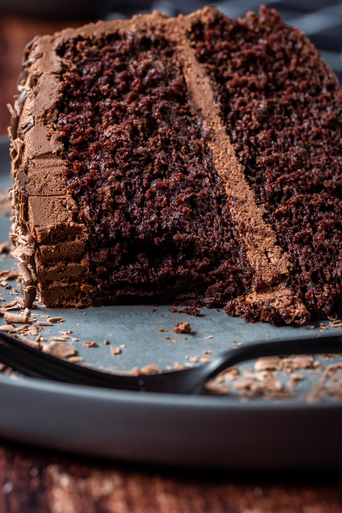 Slice of vegan chocolate fudge cake on a gray plate with a cake fork.