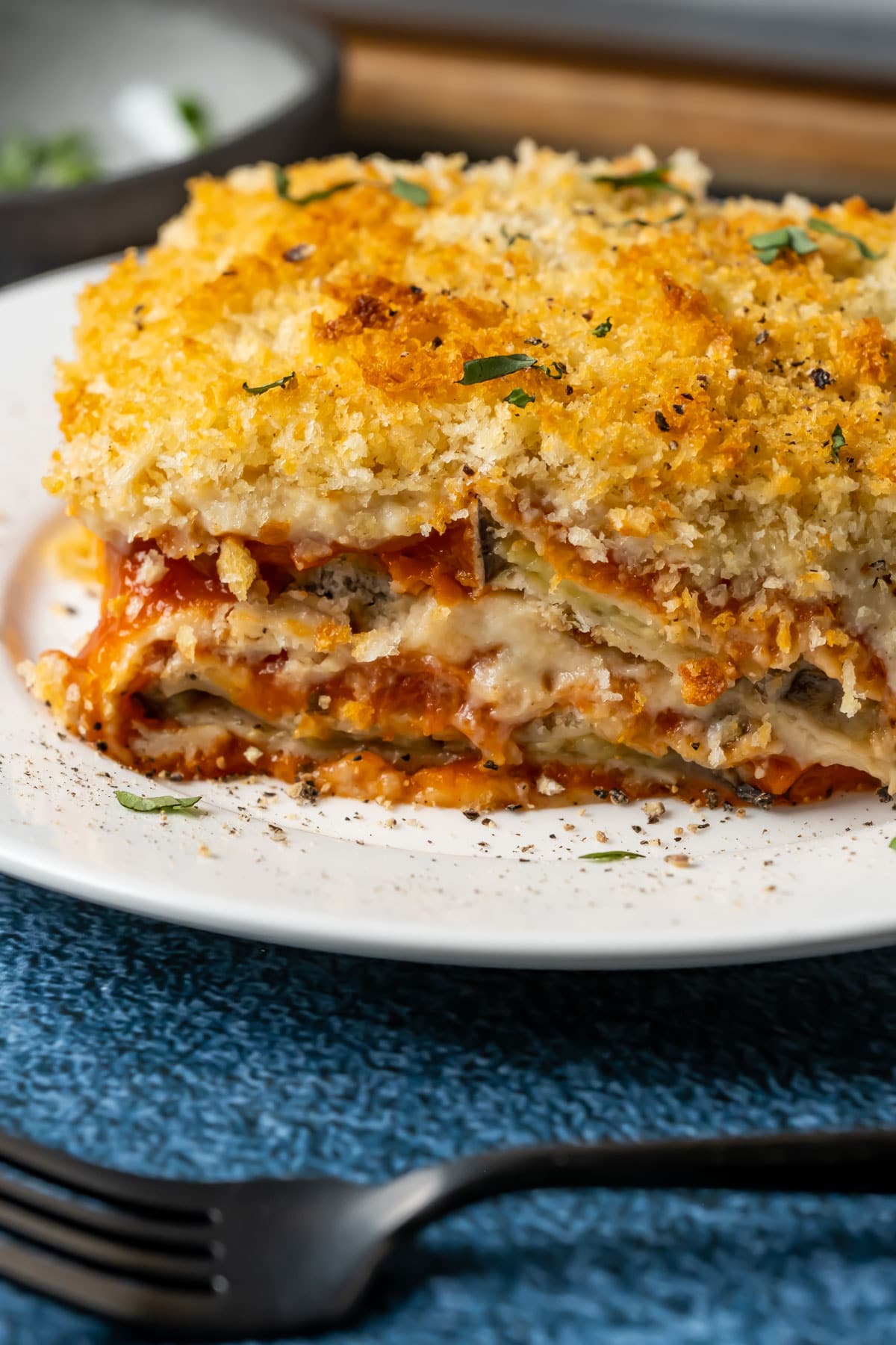 Slice of vegan eggplant parmesan on a white plate.