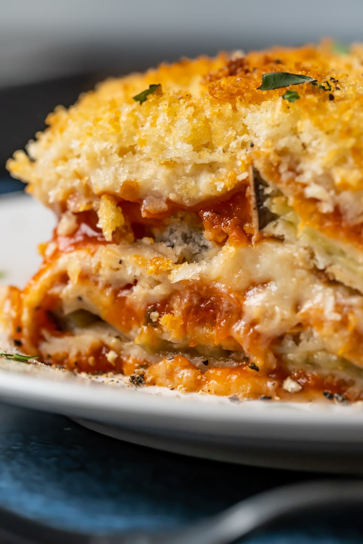 Slice of vegan eggplant parmesan on a white plate.