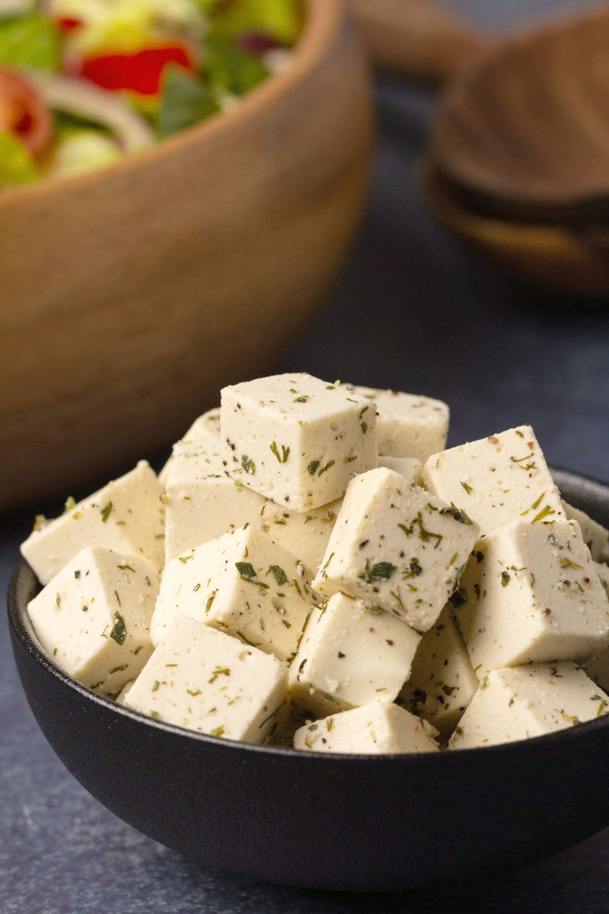 Vegan feta with oregano and dill in a black bowl. 