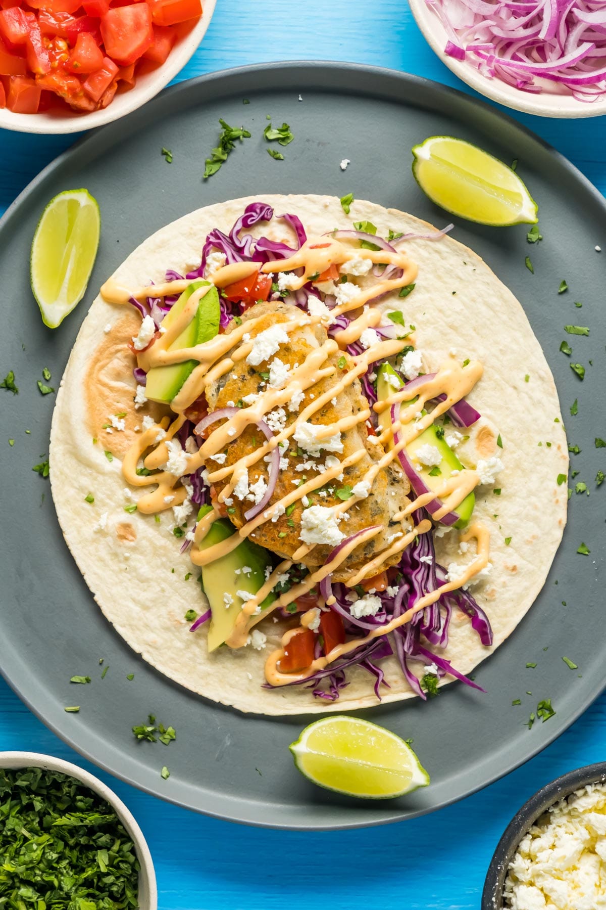 Assembling a vegan fish taco on a gray plate.