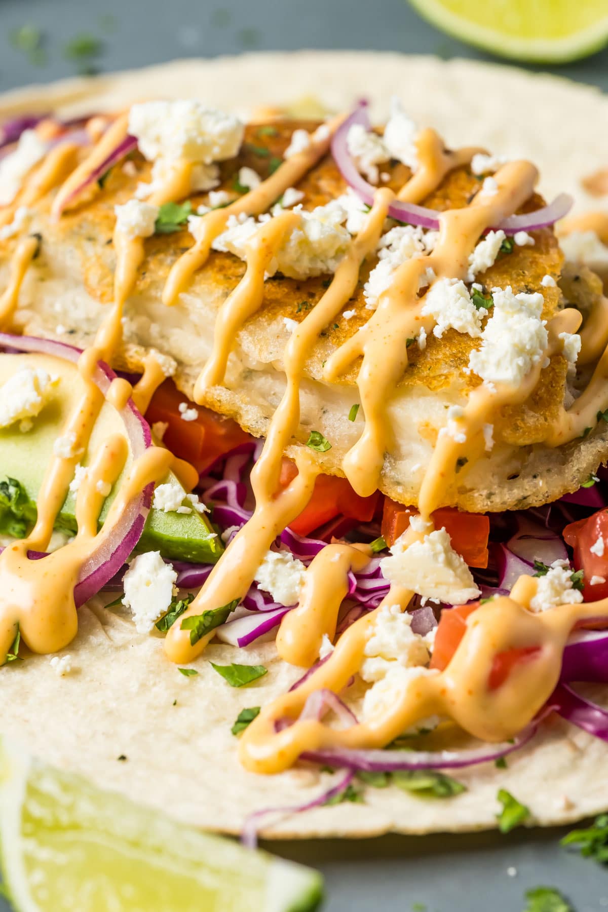 Assembling a vegan fish taco on a gray plate.