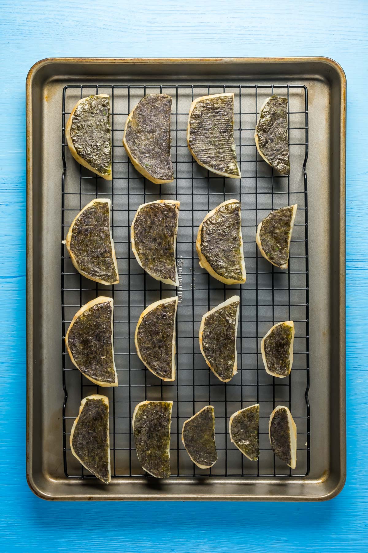 Celeriac pieces topped with seaweed on a wire rack.