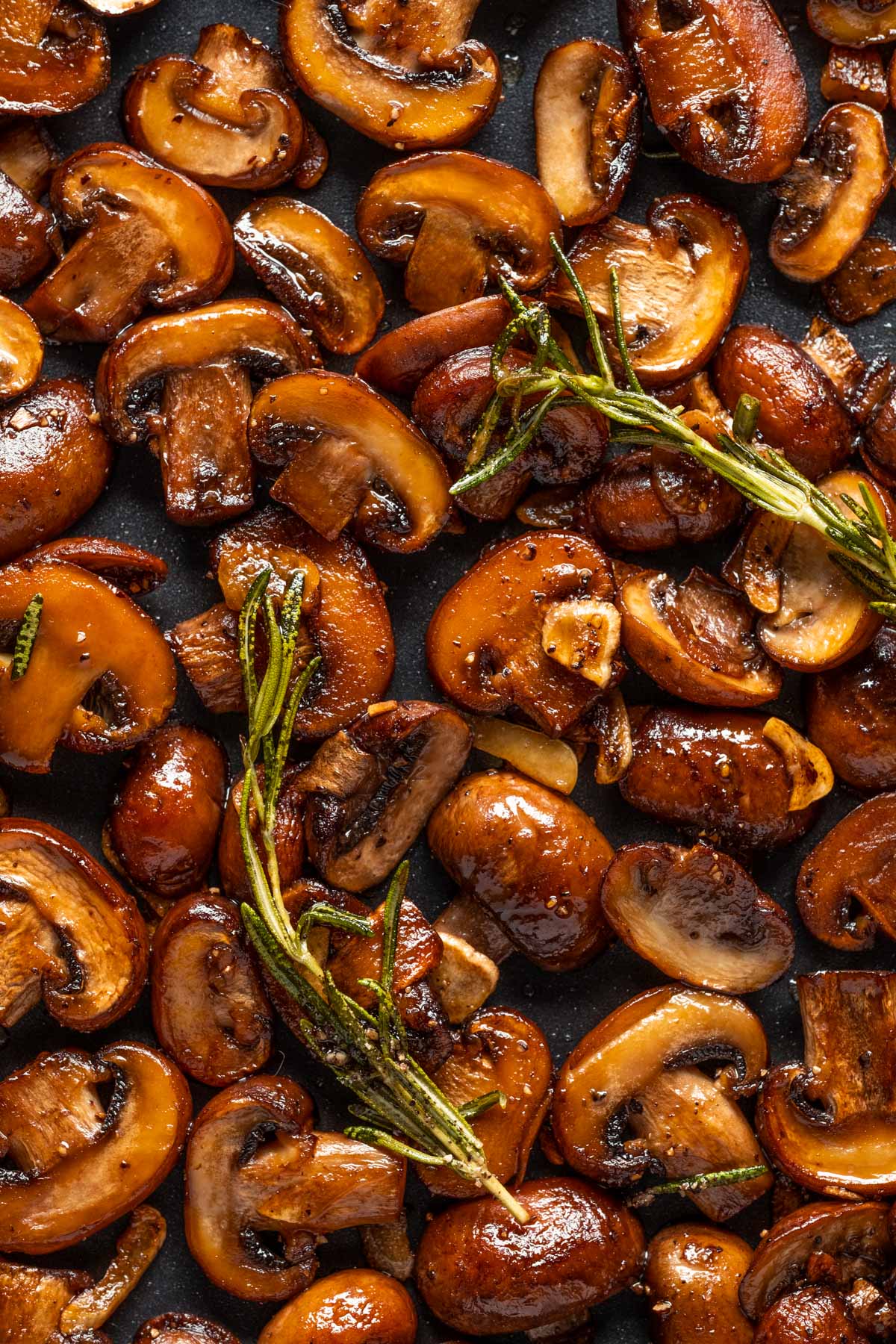 Vegan garlic mushrooms in a skillet with rosemary.