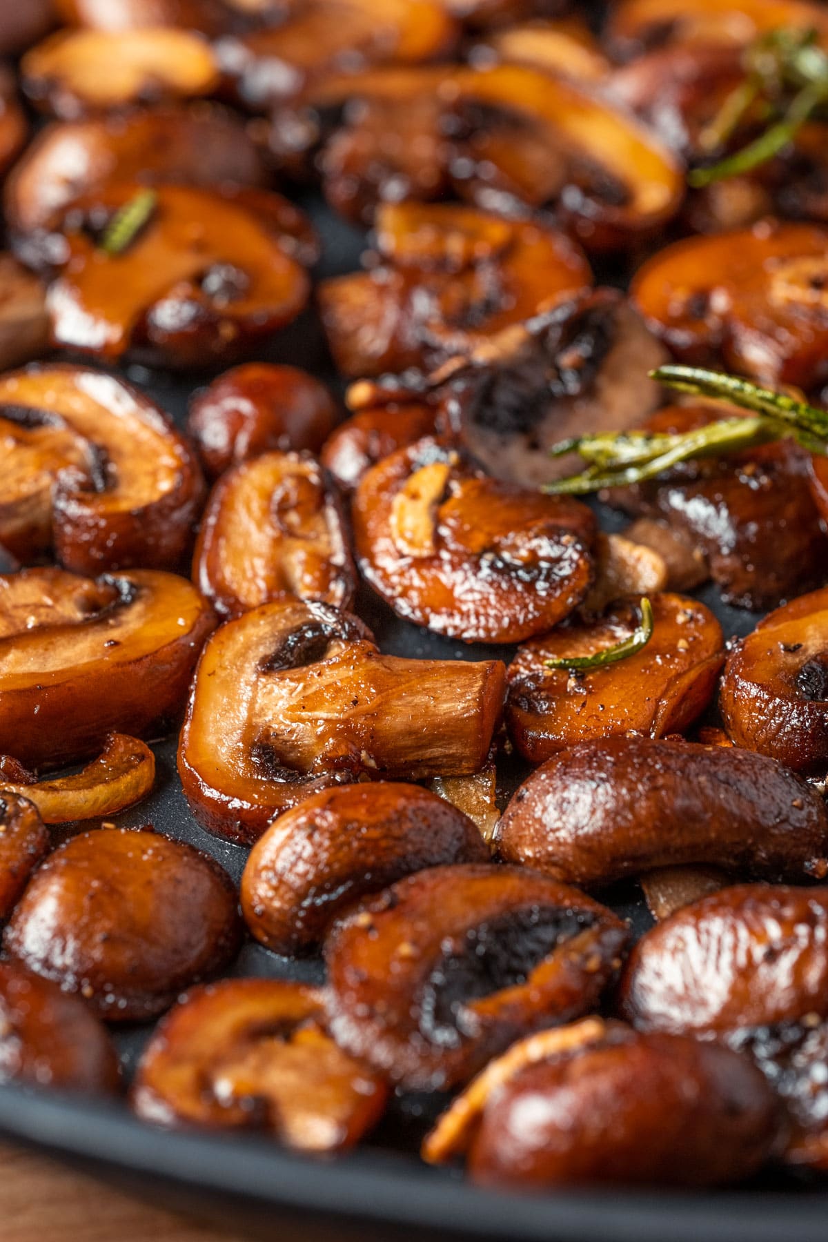 Vegan garlic mushrooms in a skillet with rosemary.