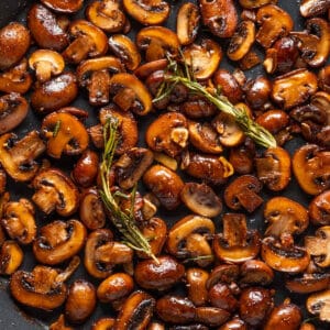 Vegan garlic mushrooms with rosemary in a skillet.