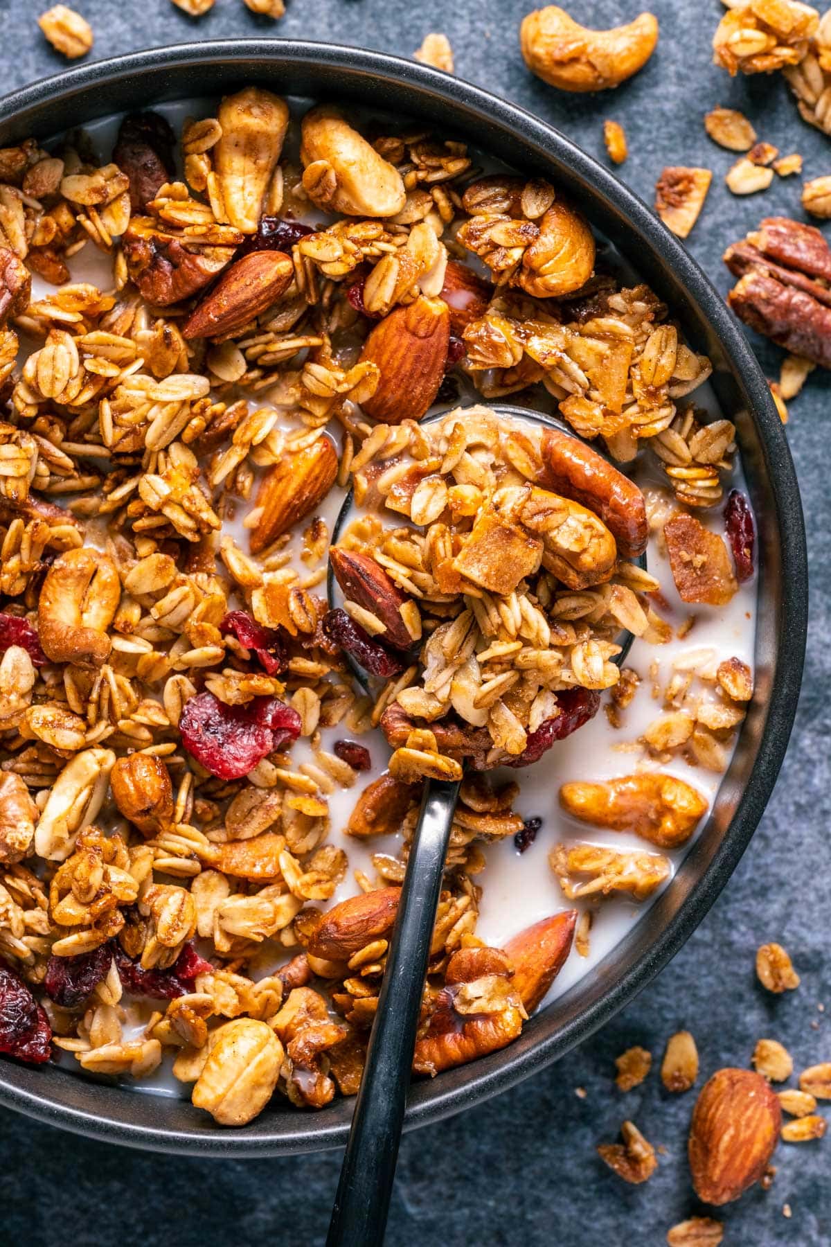 Vegan granola with almond milk in a black bowl with a spoon.