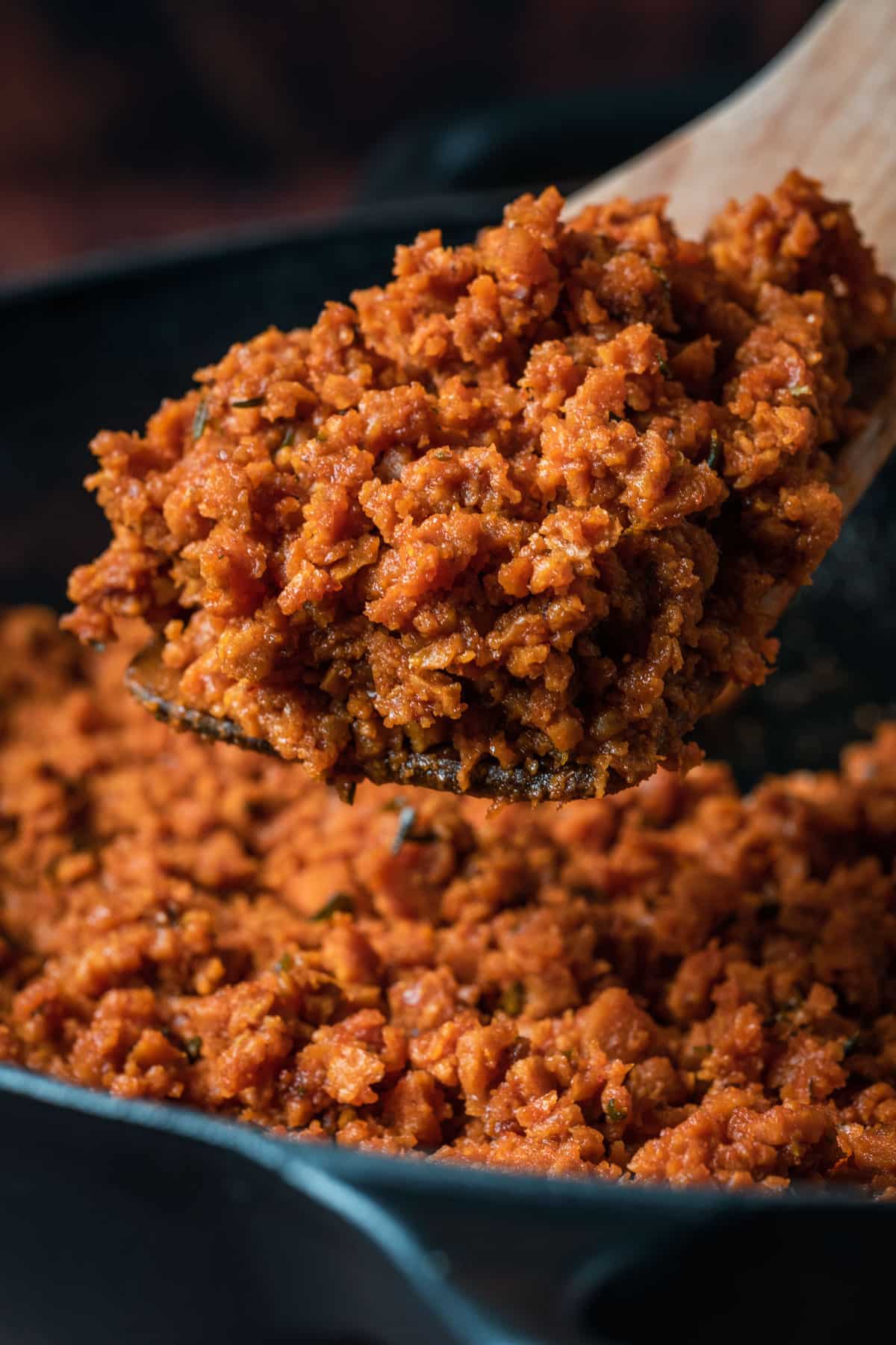 Vegan ground beef in a skillet with a wooden spoon.