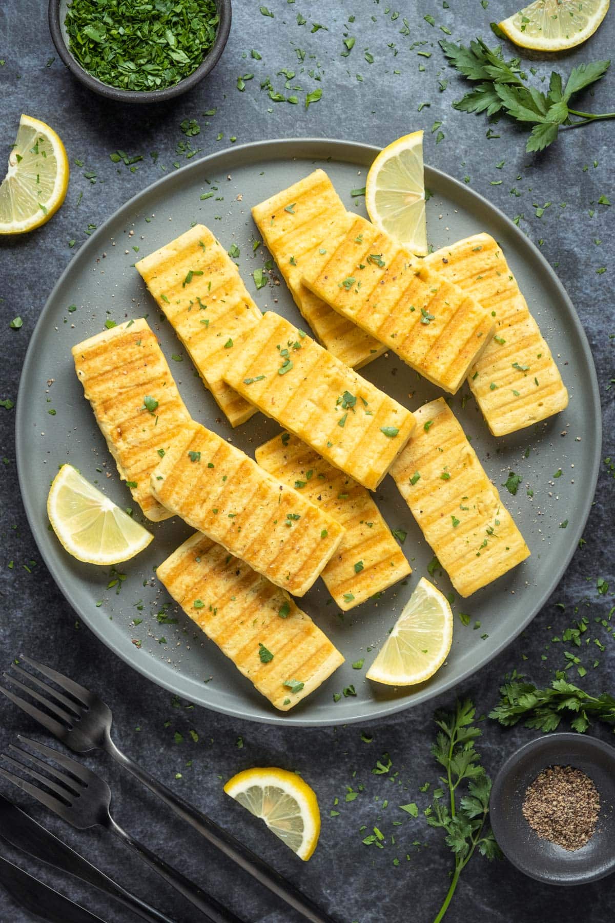 Slices of grilled vegan halloumi on a gray plate.