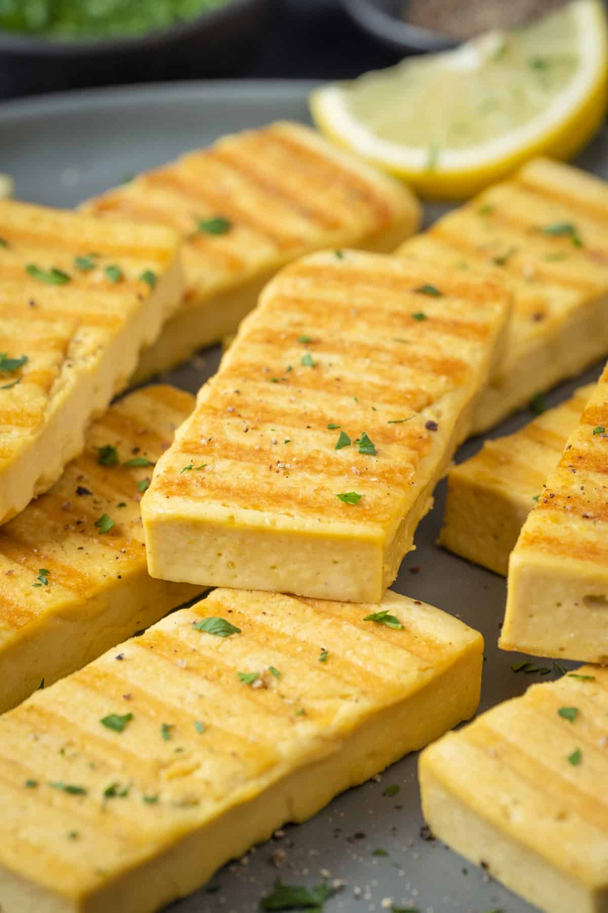 Slices of grilled vegan halloumi on a gray plate.