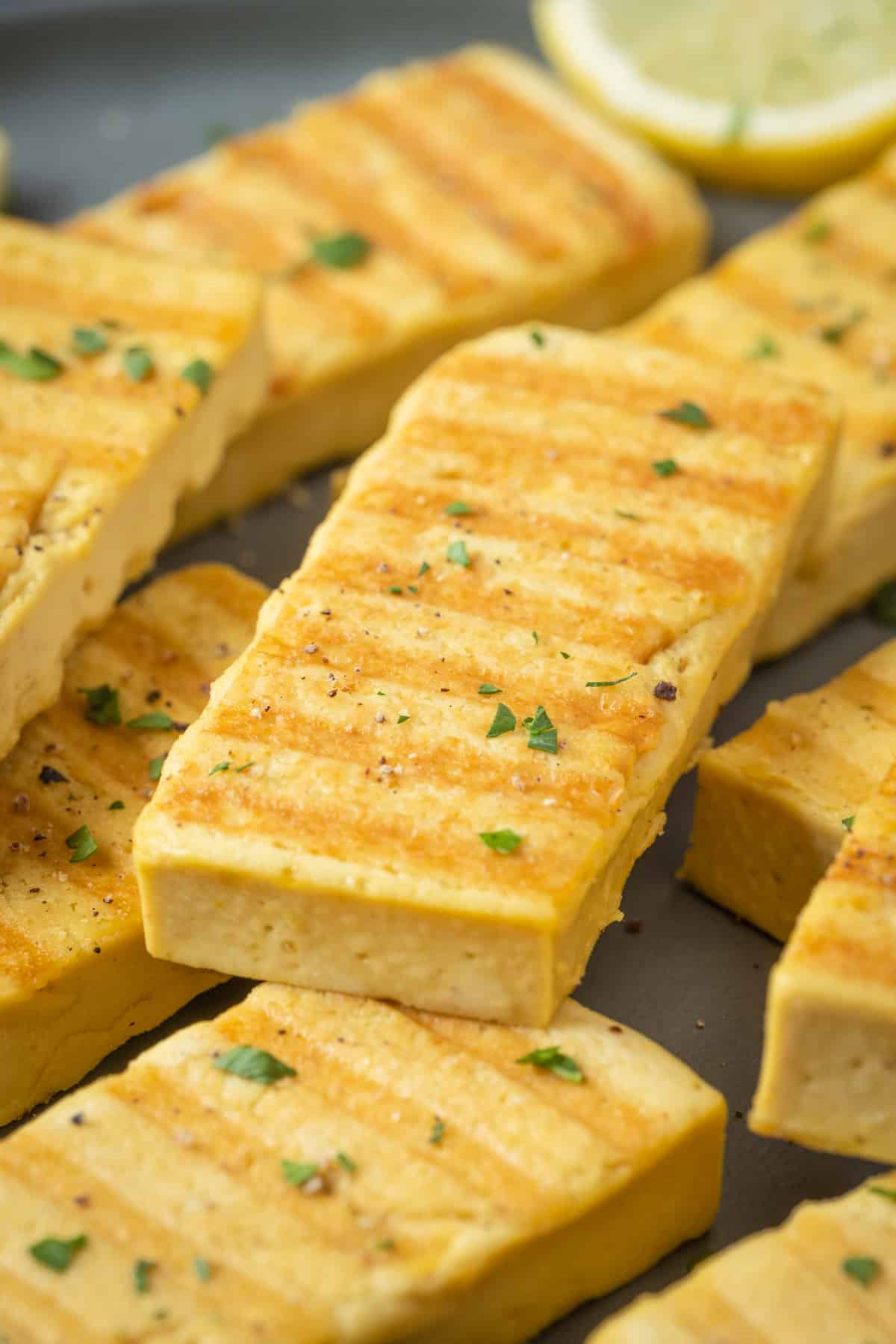 Slices of grilled vegan halloumi on a gray plate.