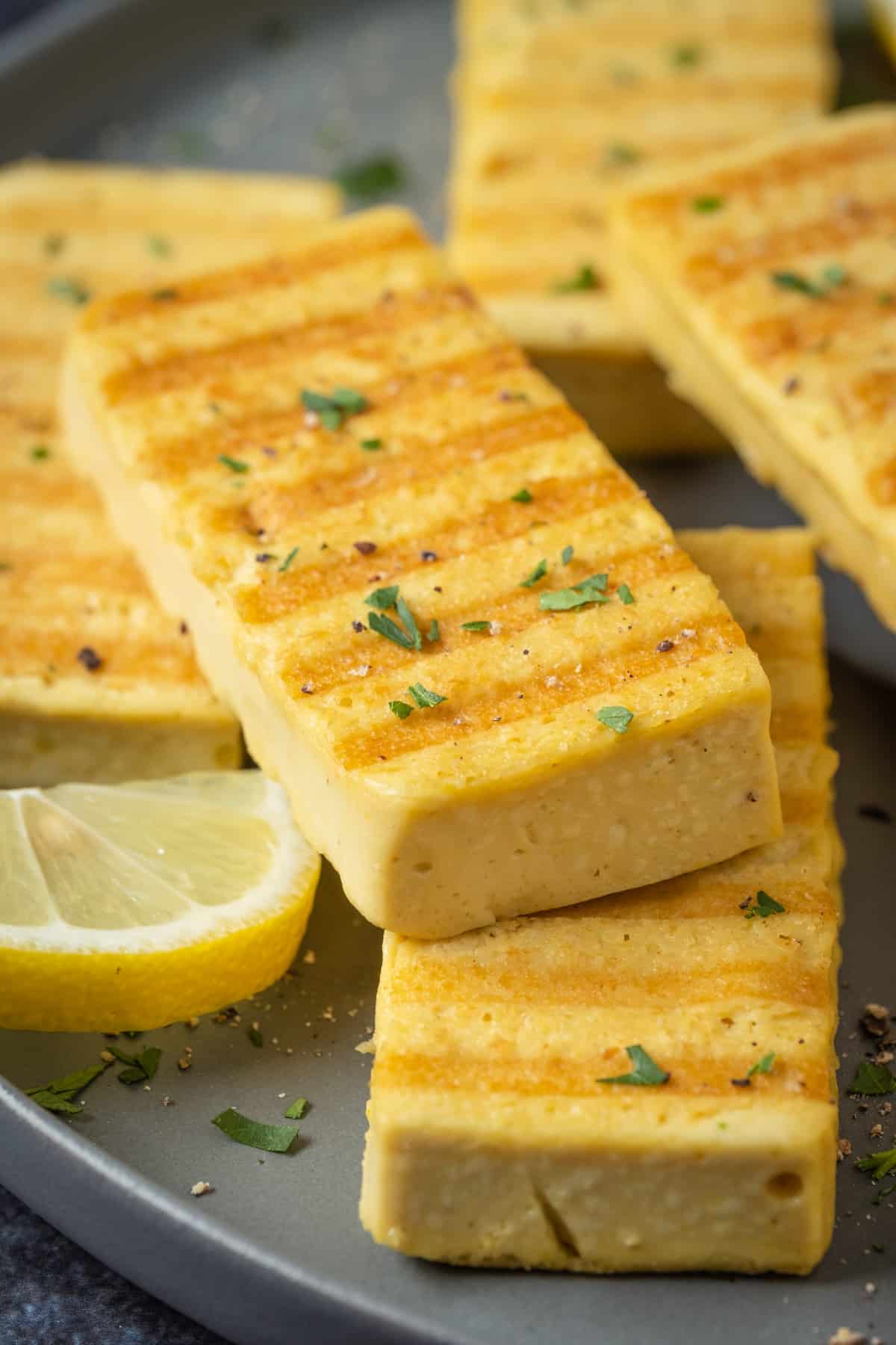 Slices of grilled vegan halloumi on a gray plate.