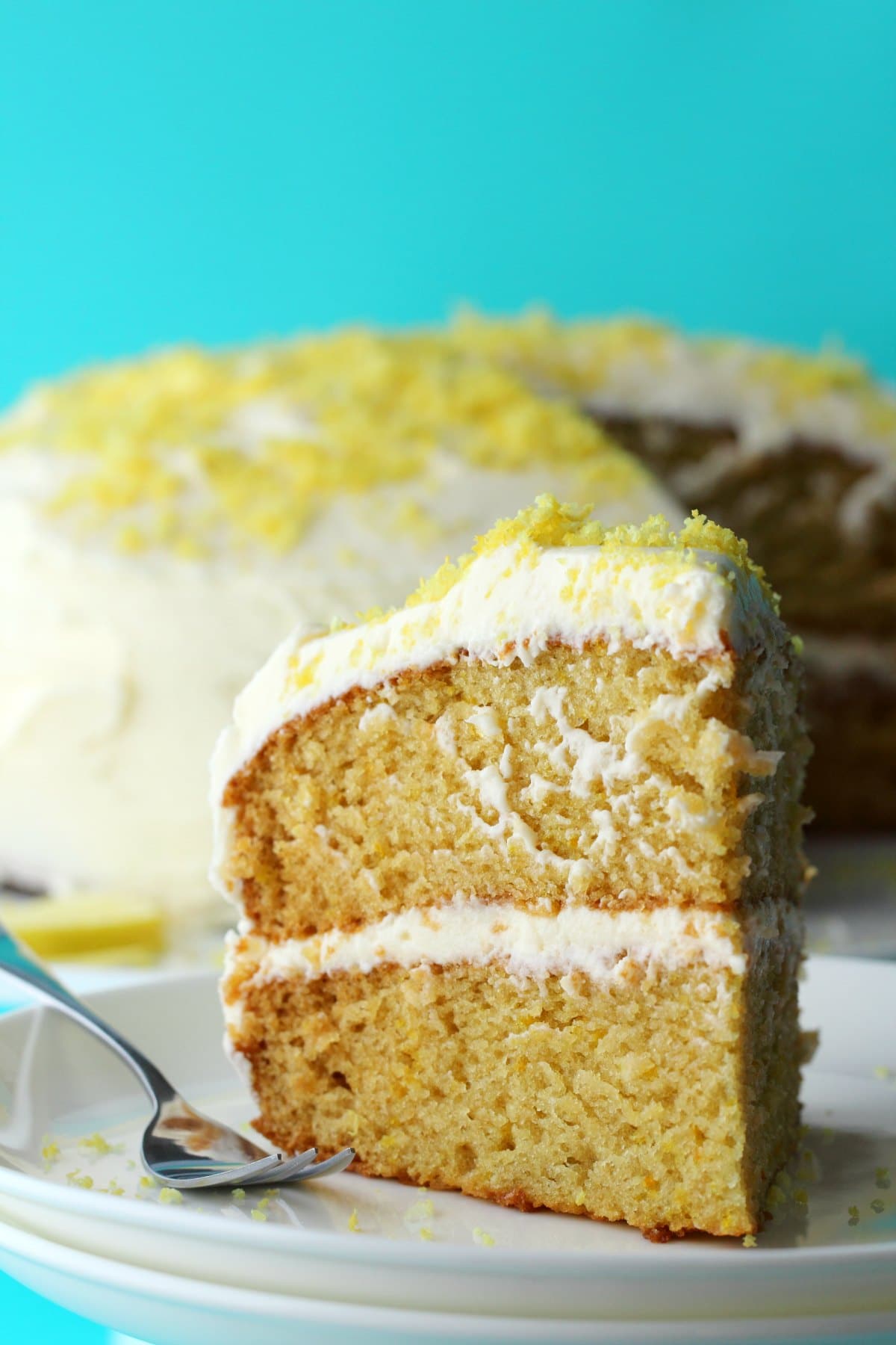 A slice of vegan lemon cake on a white plate with a cake fork. 