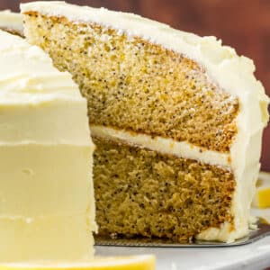 Vegan lemon poppy seed cake with slices cut on a white cake stand.