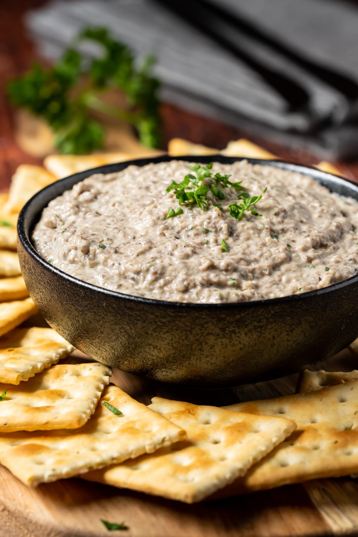 Vegan mushroom pâté in a black bowl with crackers.